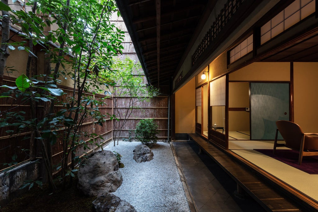 Traditional Japanese ryokan with stone pathway, lantern, and meticulously manicured garden leading to elegant wooden entrance facade