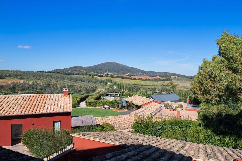 Rustic Tuscan villa with terracotta roof, stone walls, and lush green landscape, showcasing elegant outdoor seating amid scenic countryside at Scenset Rossa Resort