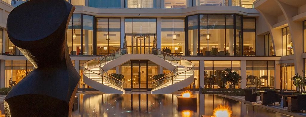 Elegant five-star hotel lobby with crystal chandeliers, marble floors, soaring columns and plush seating in warm gold and cream tones