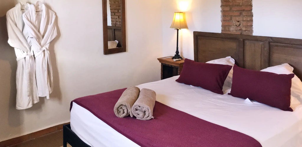 Rustic luxury suite at Cortijo del Marqués, whitewashed walls, antique wooden furniture, and soft natural light streaming through traditional Spanish windows