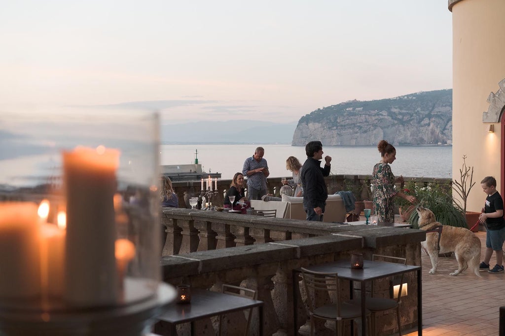 Elegant beachfront hotel with modern white balconies and terrace overlooking the Mediterranean Sea and Sorrento Marina at golden hour