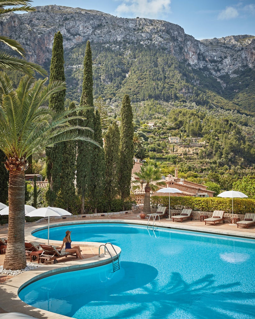 Luxurious Spanish hillside hotel with stone terraces, lush gardens, and mountain views, nestled in a charming Mediterranean village