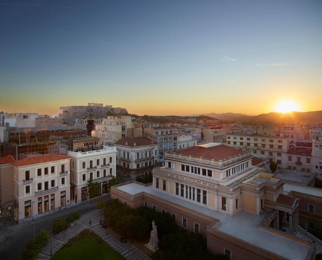 Elegant white island-style hotel featuring minimalist architecture, arched doorways and verandas overlooking the Mediterranean Sea at sunset