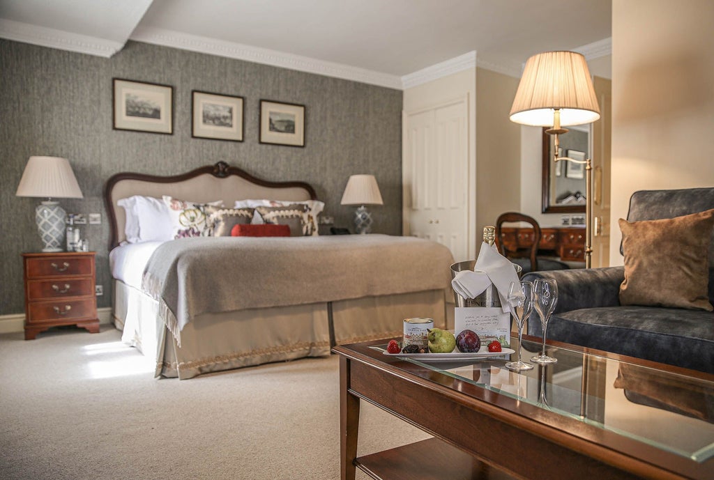 Elegant country room at scenset's luxury spa hotel with plush king bed, soft neutral tones, antique furnishings, and refined classic British countryside decor