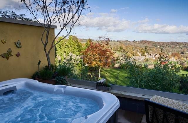 Luxurious boutique spa hotel with modern architecture, nestled in scenic UK countryside, featuring elegant stone facade and manicured gardens at sunset