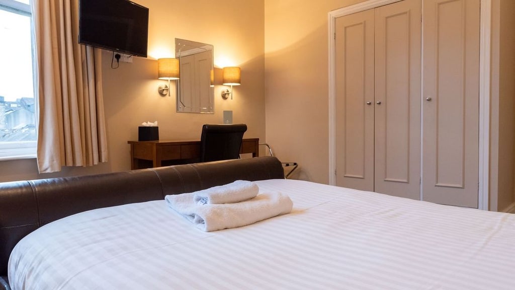 Elegant double room with plush white bedding, modern furnishings, soft ambient lighting, and city skyline view at The Scenset Hotel in the United Kingdom