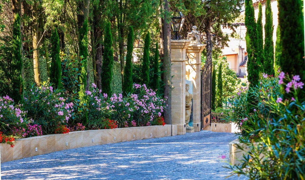 Elegant pale-blue luxury hotel with lush gardens, wrought-iron balconies, and Mediterranean stone facade nestled in scenic French countryside