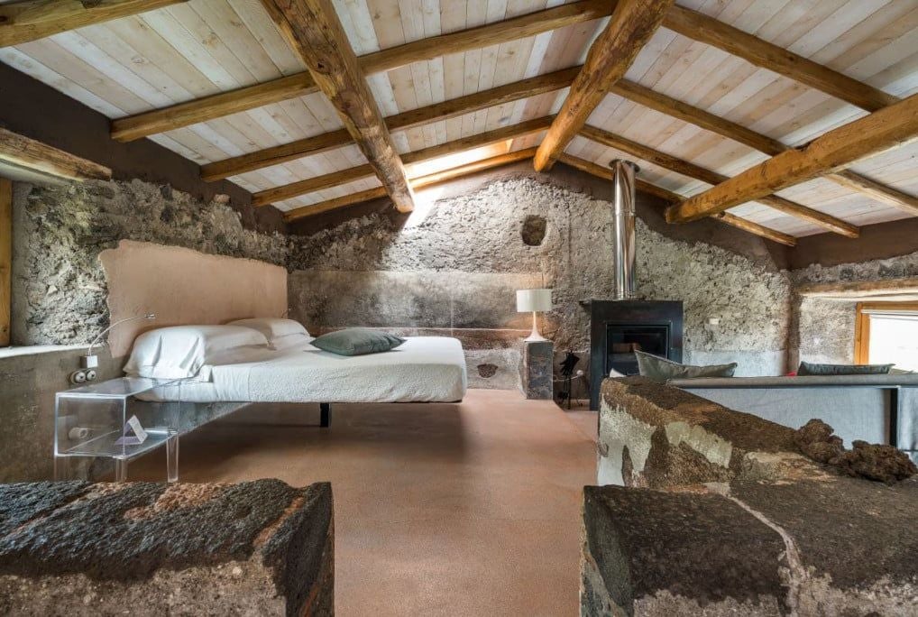 Elegant Sicilian countryside deluxe room with minimalist design, rustic wooden floors, and panoramic windows overlooking lush green vineyards and Mount Etna