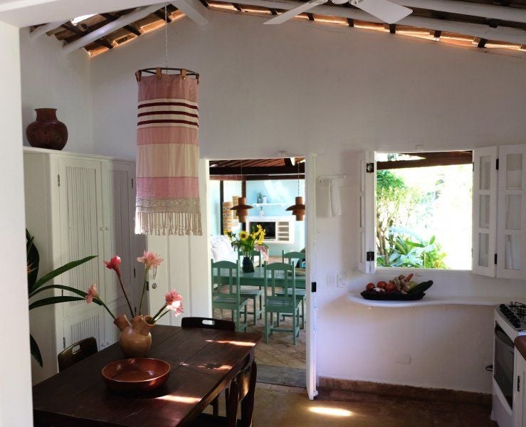 Rustic-chic Brazilian hotel room with wooden furnishings, white linens, and tropical greenery, showcasing UXUA Casa Hotel and Spa's elegant minimalist design