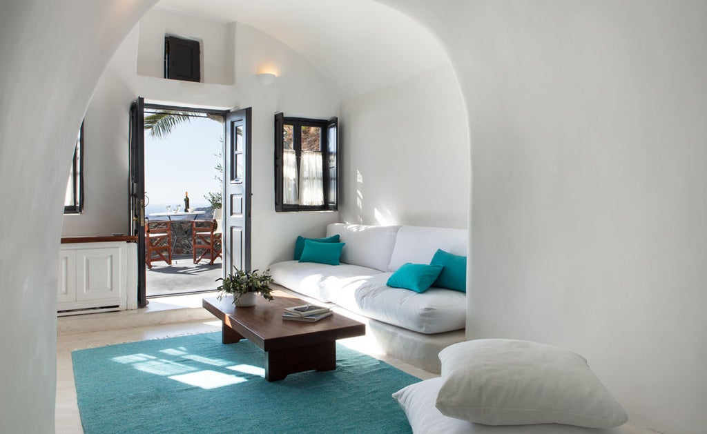 White-washed cave hotel suites cascade down Santorini cliffs, featuring infinity pools overlooking azure Aegean Sea and volcanic caldera