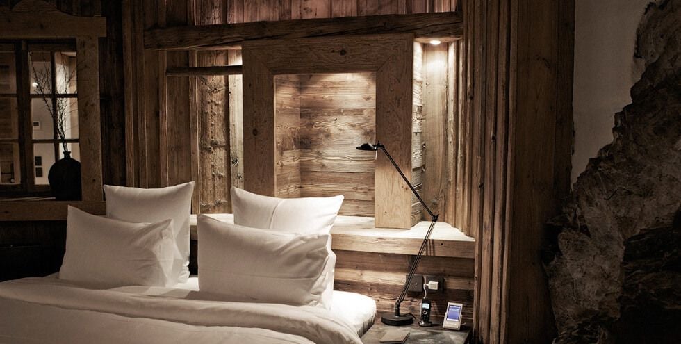 Luxurious alpine-style prestige room with wooden paneling, plush bedding, and mountain-inspired decor at a high-end French mountain resort chalet