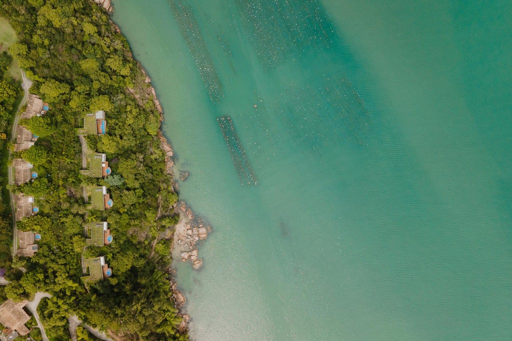 Luxurious oceanfront resort bungalow with private infinity pool overlooking emerald waters and tropical coastline at sunset in Brazil