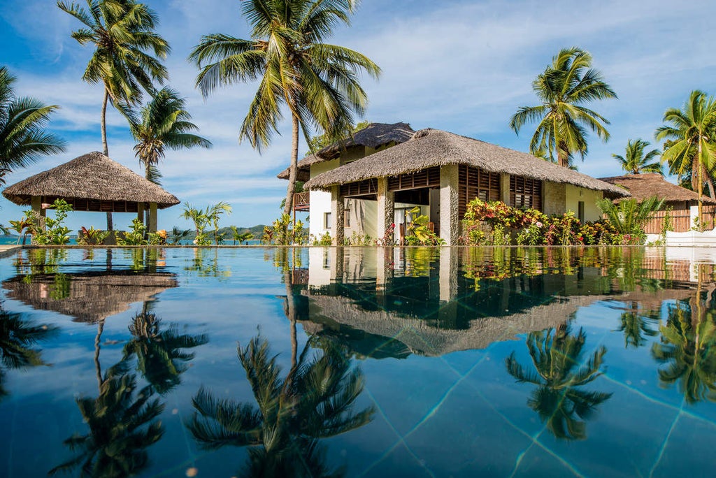 Elegant beachfront villa with thatched roof and private deck overlooking pristine turquoise waters and white sand beaches in Madagascar