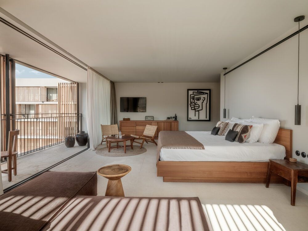 Luxurious white-themed Deluxe Junior Suite with minimalist design, featuring plush bed, elegant furnishings, and panoramic ocean view at OKU Ibiza hotel.