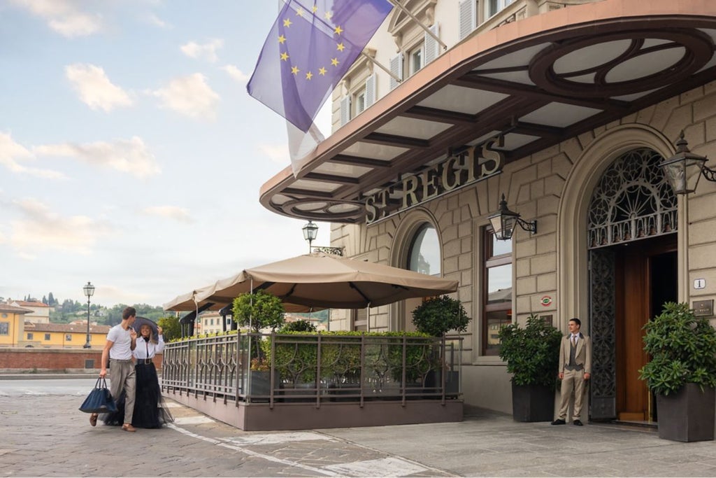 Ornate Renaissance-style facade of St Regis Florence hotel along Arno River, with elegant arched windows and classic Italian architecture