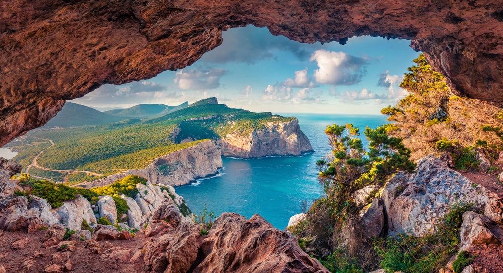 Traditional wooden boat navigates between dramatic limestone cliffs at Capri's Blue Grotto, crystal-clear turquoise waters reflect sunlight