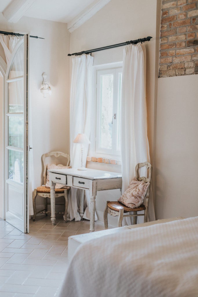 Elegant deluxe double room at Scenset hotel in Italy, featuring plush white bedding, contemporary design, and soft neutral tones with large window overlooking scenic landscape