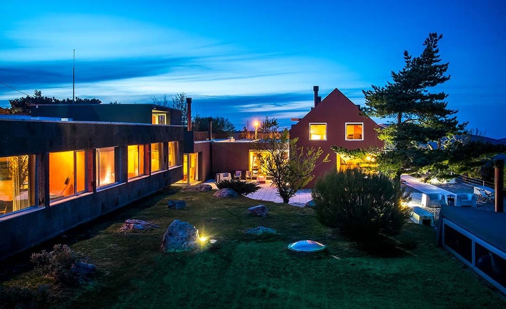 Luxurious mountain lodge with rustic wooden exterior and panoramic windows overlooking verdant Serra da Estrela landscape in Portugal