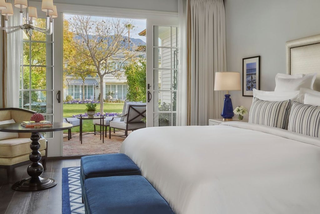 Luxurious coastal bedroom with ocean-inspired decor, crisp white linens, panoramic beach view, and elegant coastal California design details