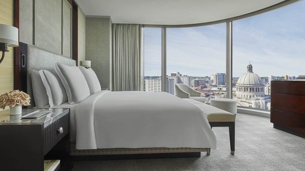 Spacious accessible hotel suite with modern luxury decor, floor-to-ceiling windows overlooking Back Bay, neutral color palette, and adaptive design features