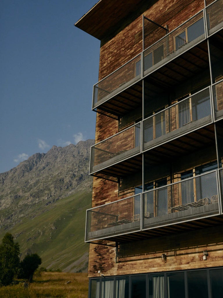 Luxurious mountain-view hotel room with modern minimalist design, floor-to-ceiling windows, and panoramic Caucasus Mountains scenery at scenset resort