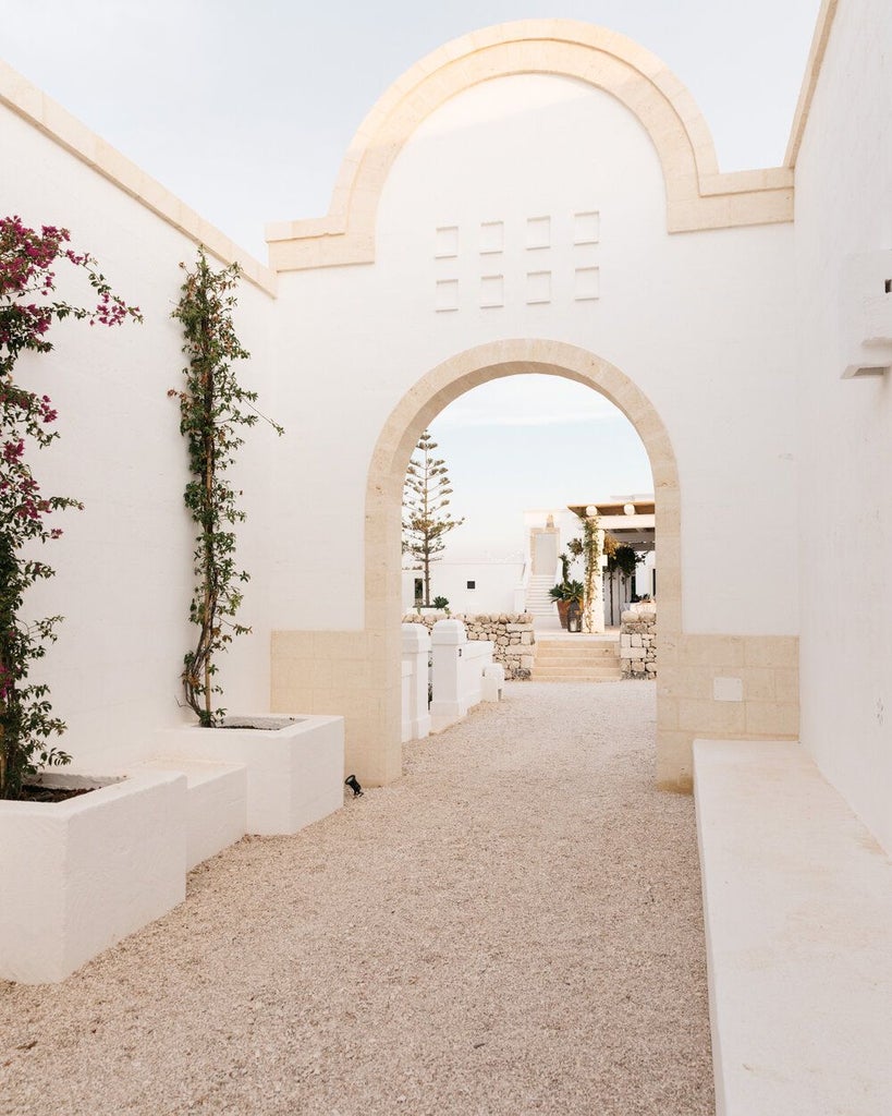 Luxurious rustic stone villa nestled in scenic Puglia countryside, with sun-drenched stone walls, olive trees, and azure Mediterranean light