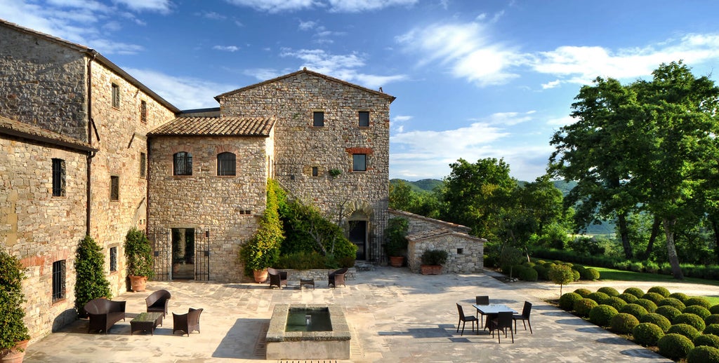 Historic Italian castle-turned-luxury hotel with stone walls, surrounded by manicured gardens and rolling Umbrian countryside hills