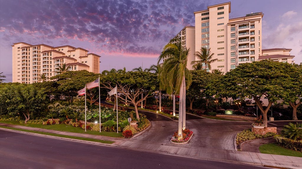 Luxurious oceanfront resort with palm trees, golden sunset, infinity pool overlooking azure Hawaiian waters at Scenset's tropical beachfront property