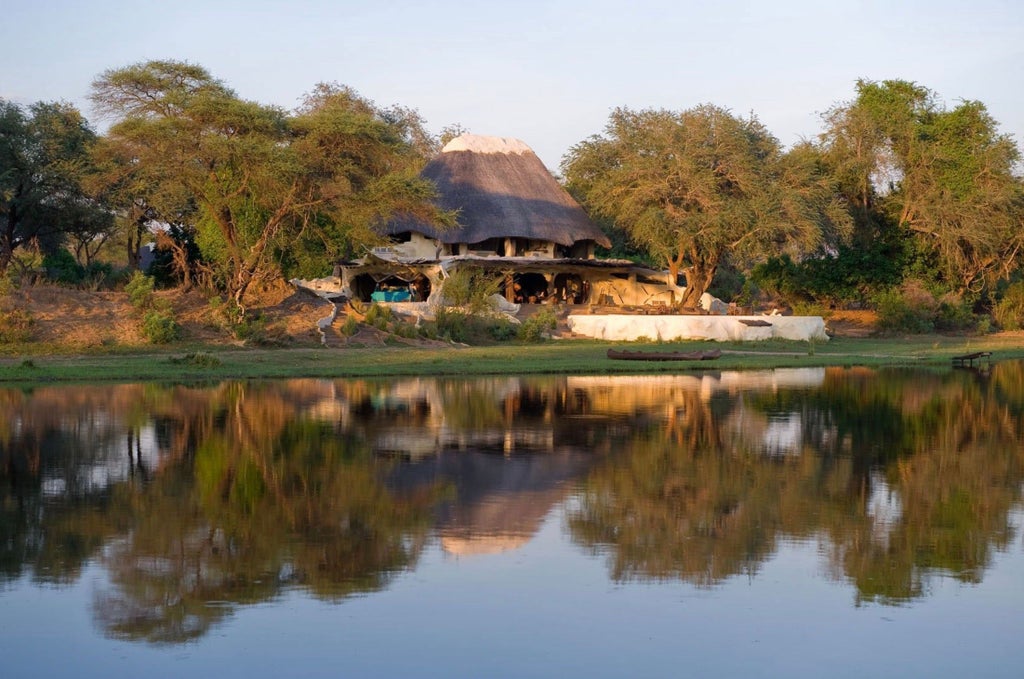 Luxurious open-air riverside villa with thatched roof, stone walls and natural wood accents overlooking the Lower Zambezi National Park