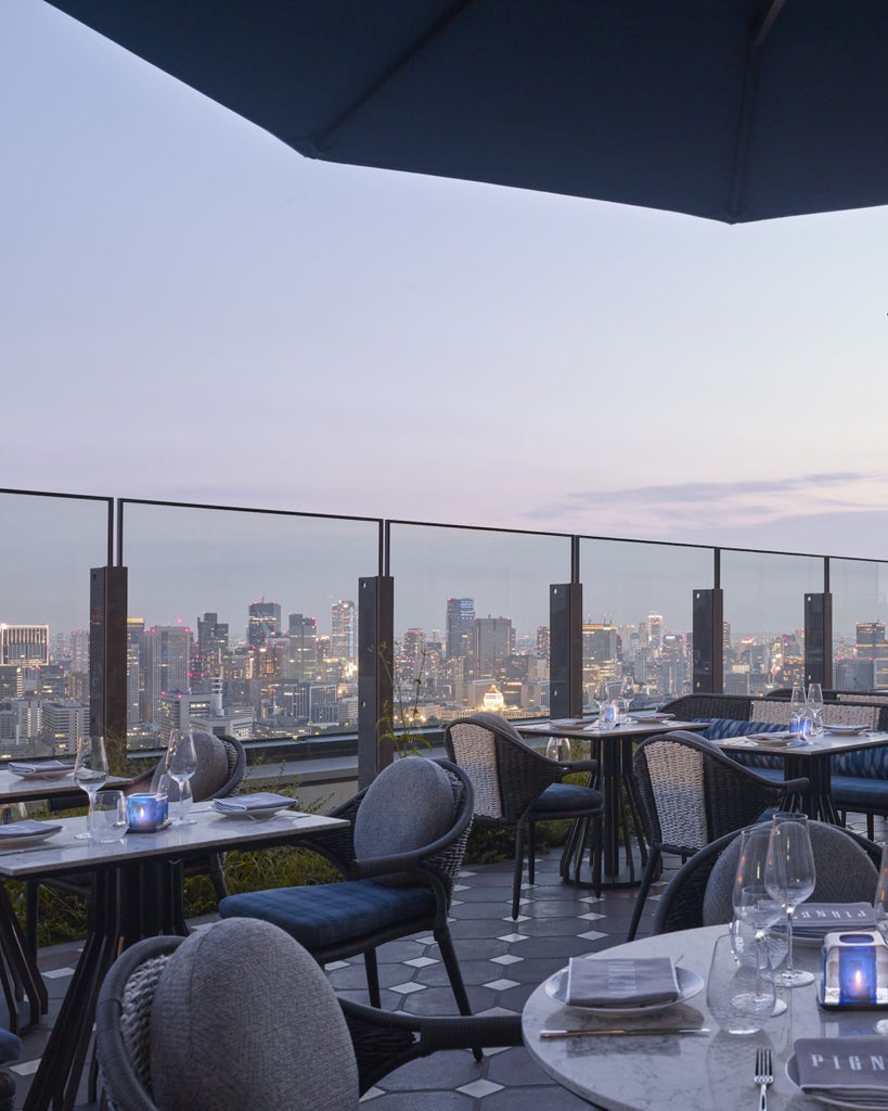 Sleek modern high-rise hotel tower in Tokyo with floor-to-ceiling windows, featuring elegant Japanese design and illuminated against evening sky