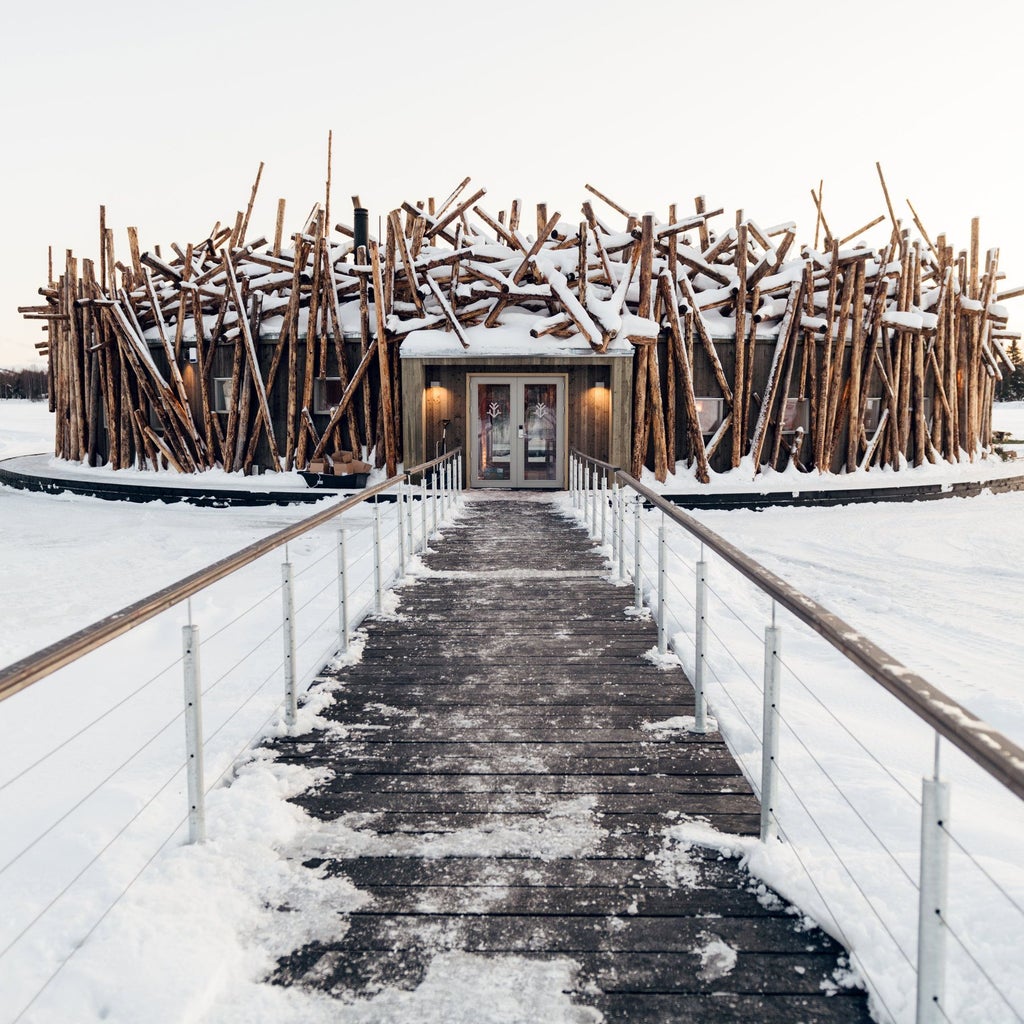 Luxurious circular floating hotel with wooden exterior, suspended over frozen river, surrounded by snow-covered trees in Arctic Swedish landscape