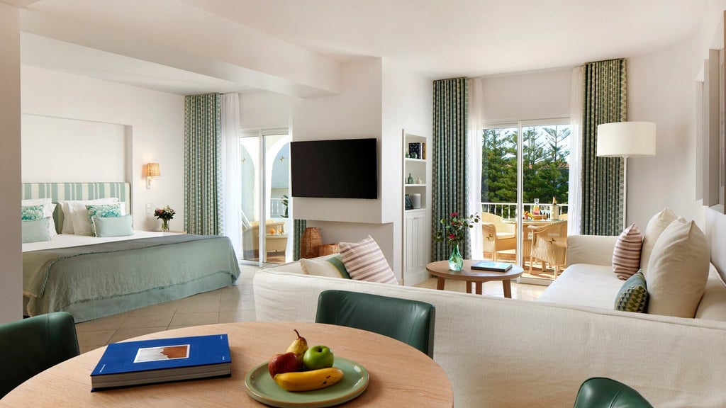 Spacious luxury family suite with elegant white decor, contemporary furnishings, two plush beds, and panoramic coastal view of Portuguese Algarve resort