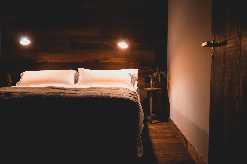 Cozy mountain lodge bedroom with rustic wooden furniture, plush bedding, and panoramic alpine views in a serene Andorran accommodation setting