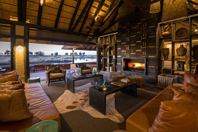 Elegant thatched-roof luxury suite overlooking Linyanti River, with private plunge pool and outdoor terrace surrounded by African bush