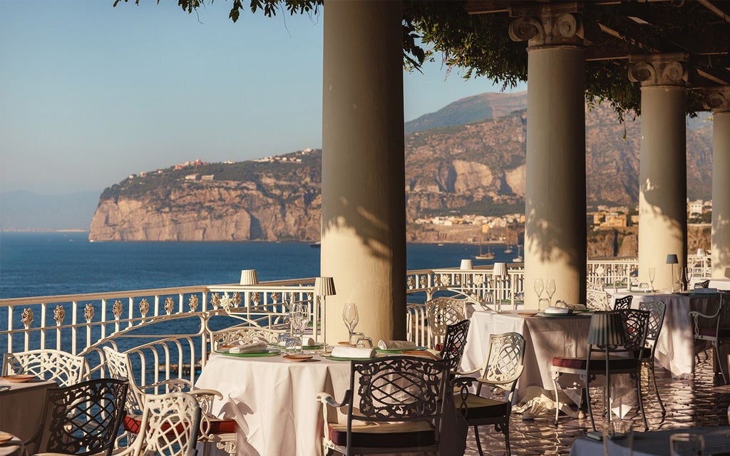 Luxurious seaside hotel perched on Sorrento's cliffside, featuring elegant Mediterranean architecture with sweeping views of azure coastline and vibrant sunset