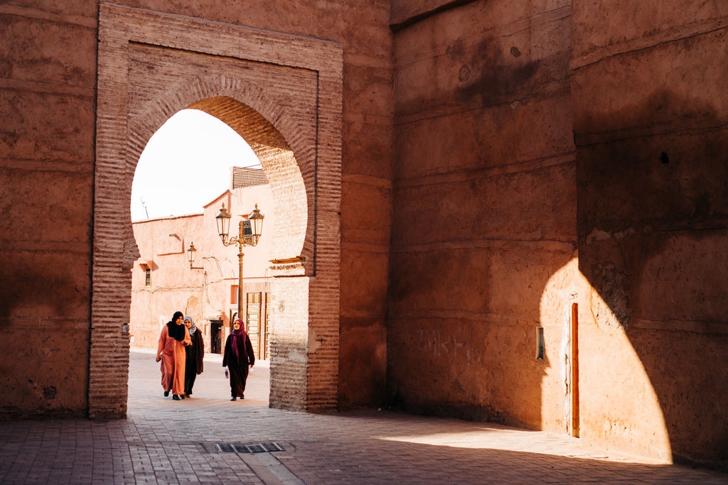 Sun-drenched courtyards of Marrakech's ancient medina showcase ornate archways, intricate tilework, and palm trees against terracotta walls