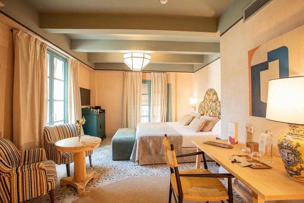 Elegant whitewashed superior room with traditional Spanish architecture, wooden furnishings, and soft neutral tones in a historic Seville hotel setting