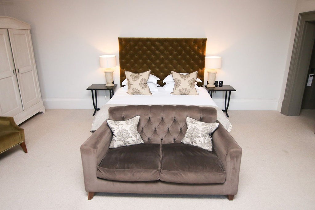 Elegant king-sized bed with rich textured headboard, plush white bedding, and soft ambient lighting in luxurious United Kingdom hotel room