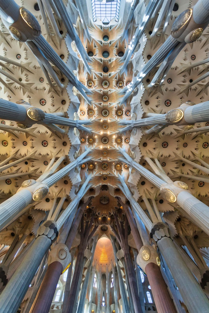 Ornate Gaudí architecture in Barcelona, intricate mosaic details of La Sagrada Familia with sunlight cascading across elaborate stone facades and vibrant tile work