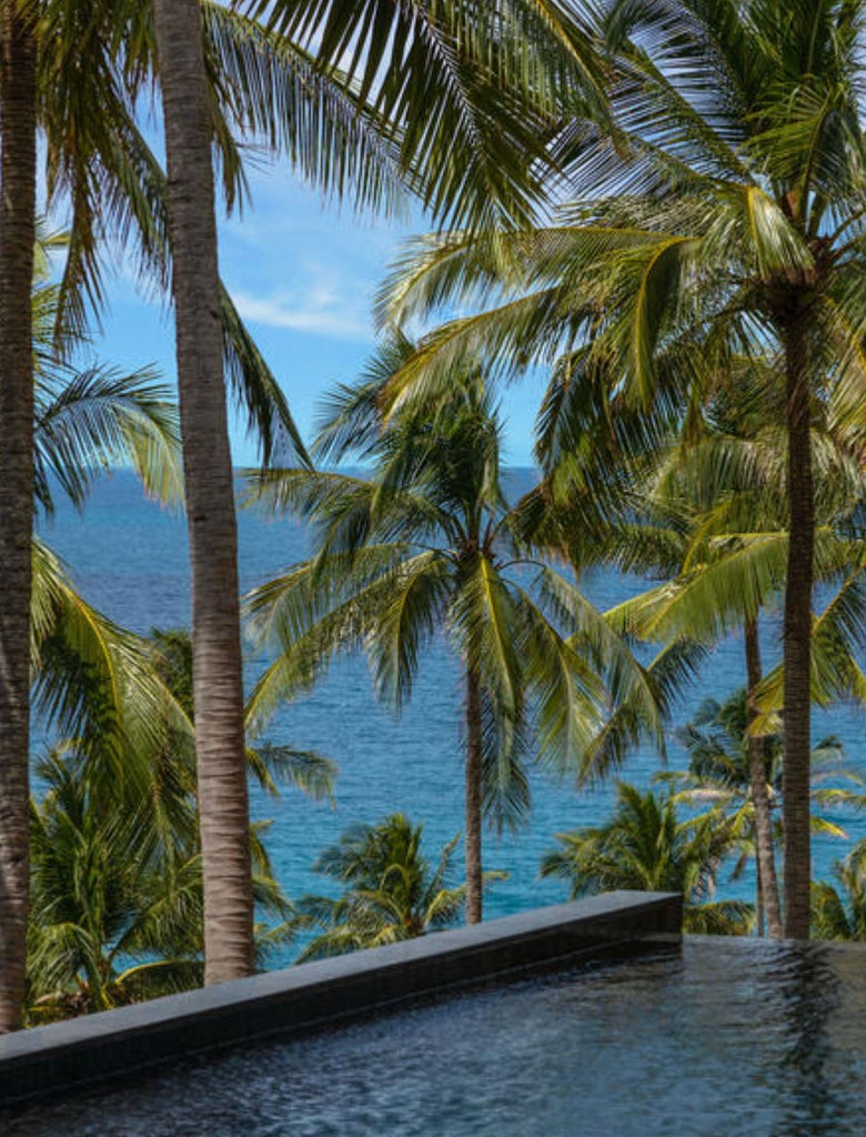 Elegant luxury pavilion with infinity pool overlooking Andaman Sea, featuring teak accents and lush tropical landscaping at dusk