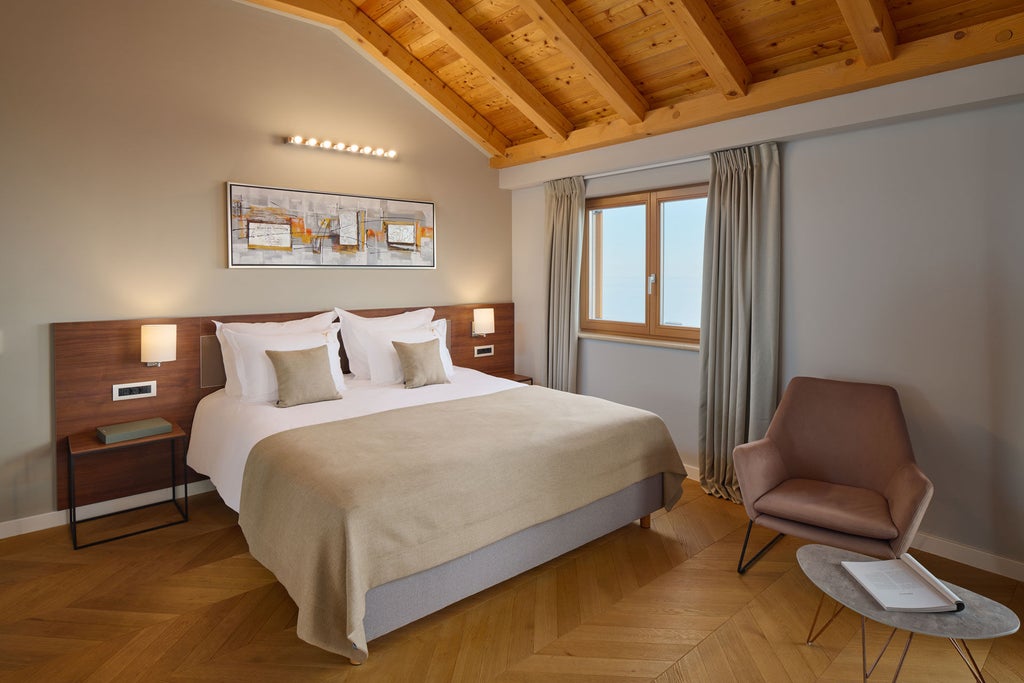 Elegant hotel suite with private furnished balcony overlooking Croatian coast, featuring modern decor, king bed and marble bathroom