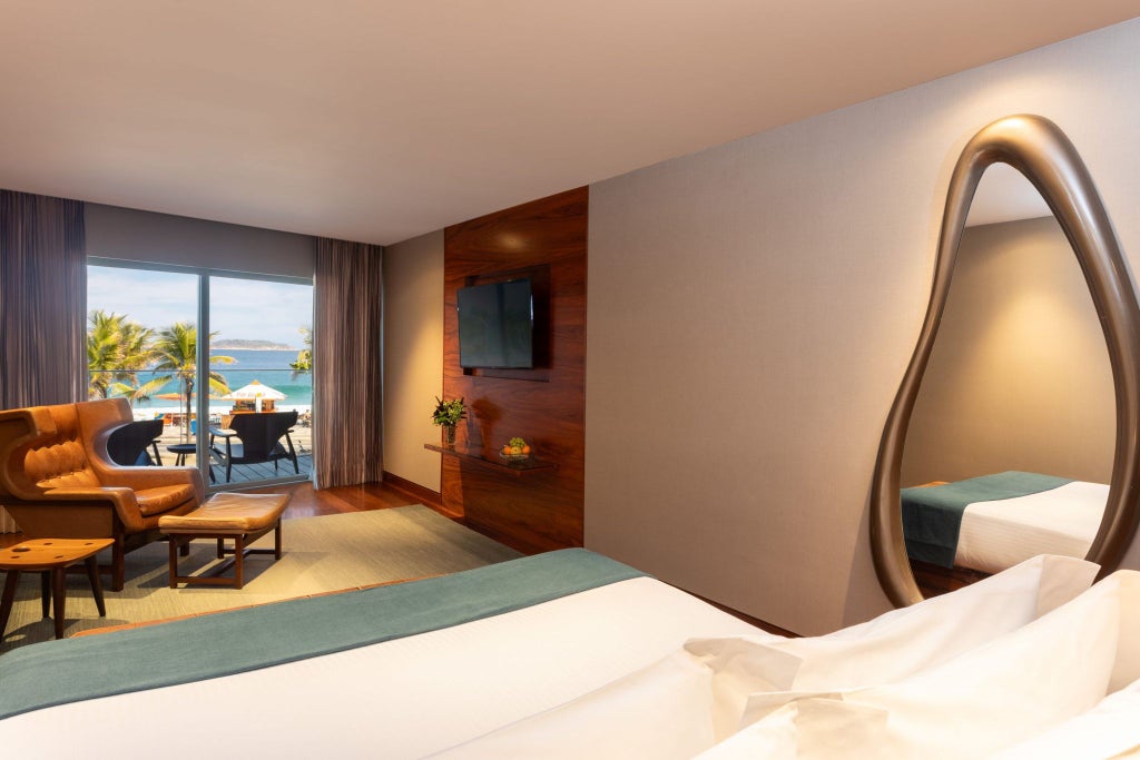 Elegant Fasano Rio hotel suite with sweeping ocean views, modern minimalist decor, plush king bed, and floor-to-ceiling windows overlooking Copacabana Beach