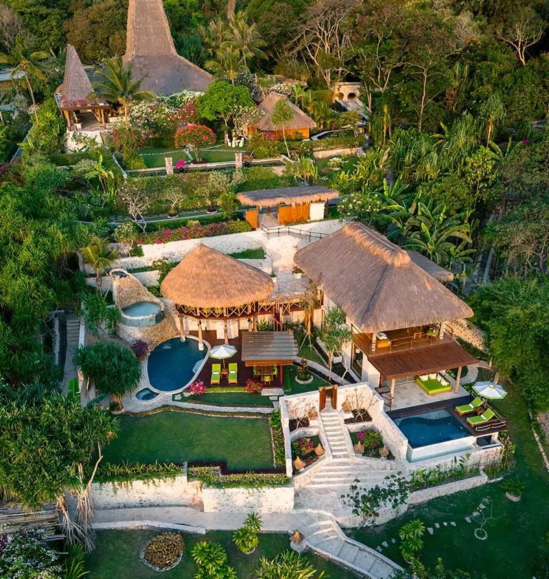 Luxurious open-air bedroom in NIHI Sumba's Wamoro Estate, overlooking lush tropical landscape with expansive wooden deck and infinity pool