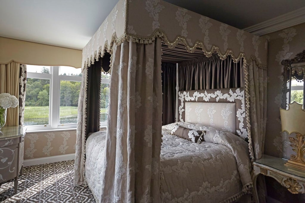 Elegant castle hotel room with four-poster bed, antique furniture, crystal chandelier, rich fabrics, and large windows overlooking gardens