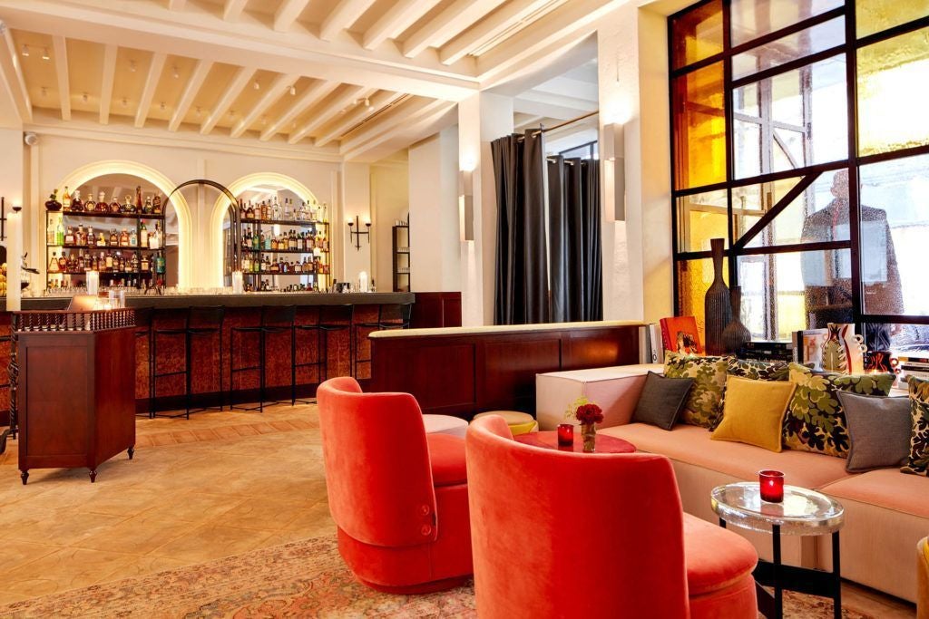 Luxurious boutique hotel lobby with dimly lit Art Deco design, plush velvet seating, and moody atmospheric lighting in Paris