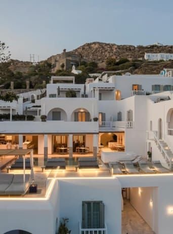 Luxurious white-washed Cycladic hotel overlooking azure Aegean waters, featuring minimalist design with crisp architectural lines and infinity pool