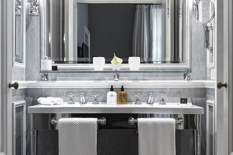 Elegant marble-toned junior suite balcony at luxury hotel in Roma, overlooking historic streetscape with ornate architectural details and soft Italian sunlight