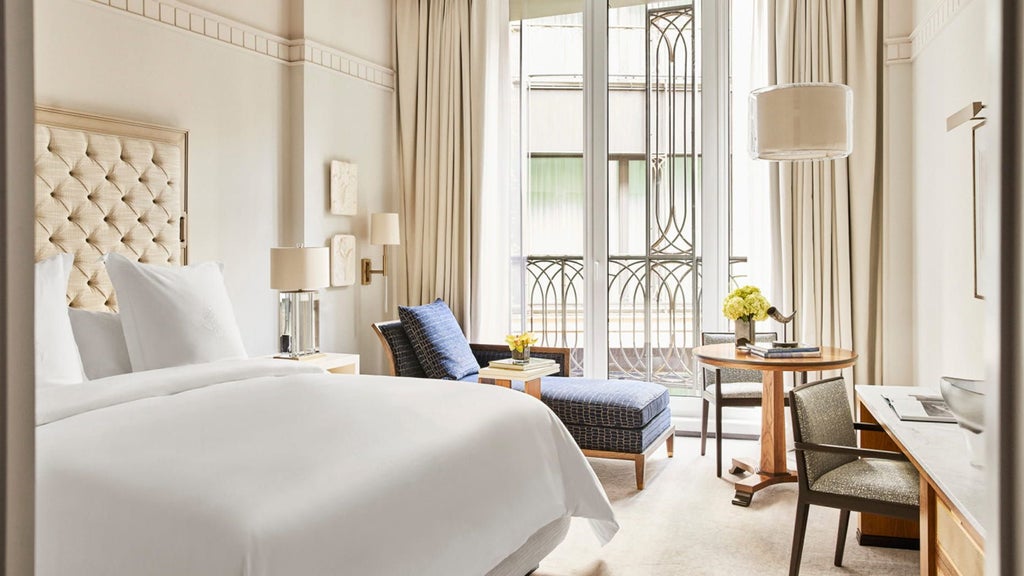 Elegant hotel room with plush king bed, marble bathroom, ornate gold fixtures, and expansive courtyard views through floor-to-ceiling windows