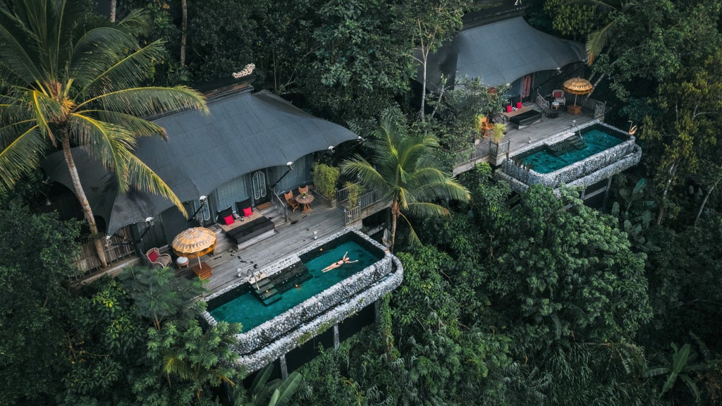 Opulent tent-style suite overlooking lush valley with private infinity pool, contemporary decor, and floor-to-ceiling windows at sunset