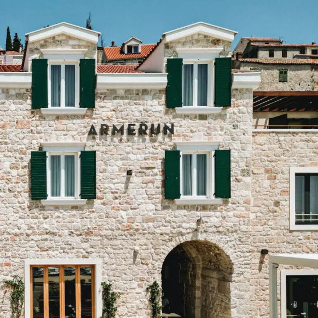 Five-star Hotel Armerun's elegant beachfront facade with palm-lined infinity pool overlooking the crystal-clear Adriatic Sea at sunset